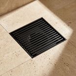 Square stainless steel floor drain with linear grate, laser-welded frame construction and powder-coated surface finish