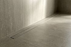 Tile-in linear stainless steel floor drain with recessed channel, designed for wall-side installation and seamless floor integration